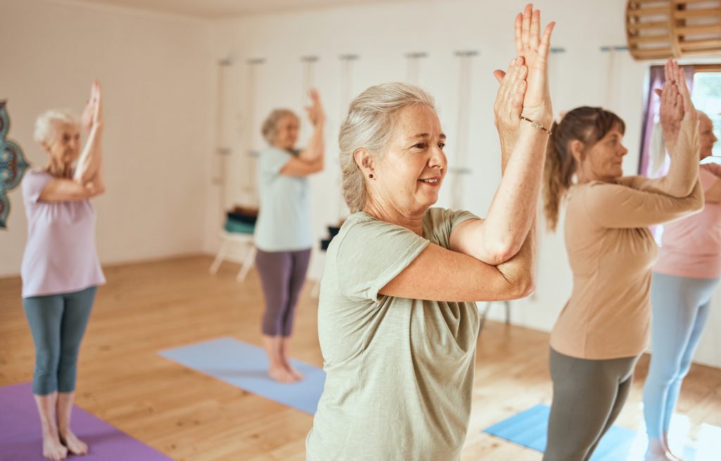 women doing yoga in an exercise studio with soft light and warm wooden flooring