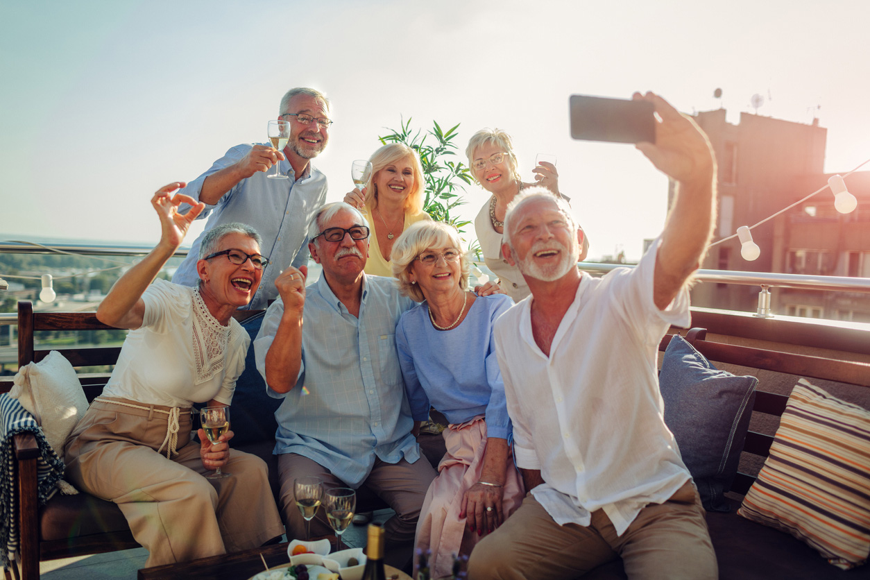 a group of seven residents take a selfie and raise a toast on an outdoor deck